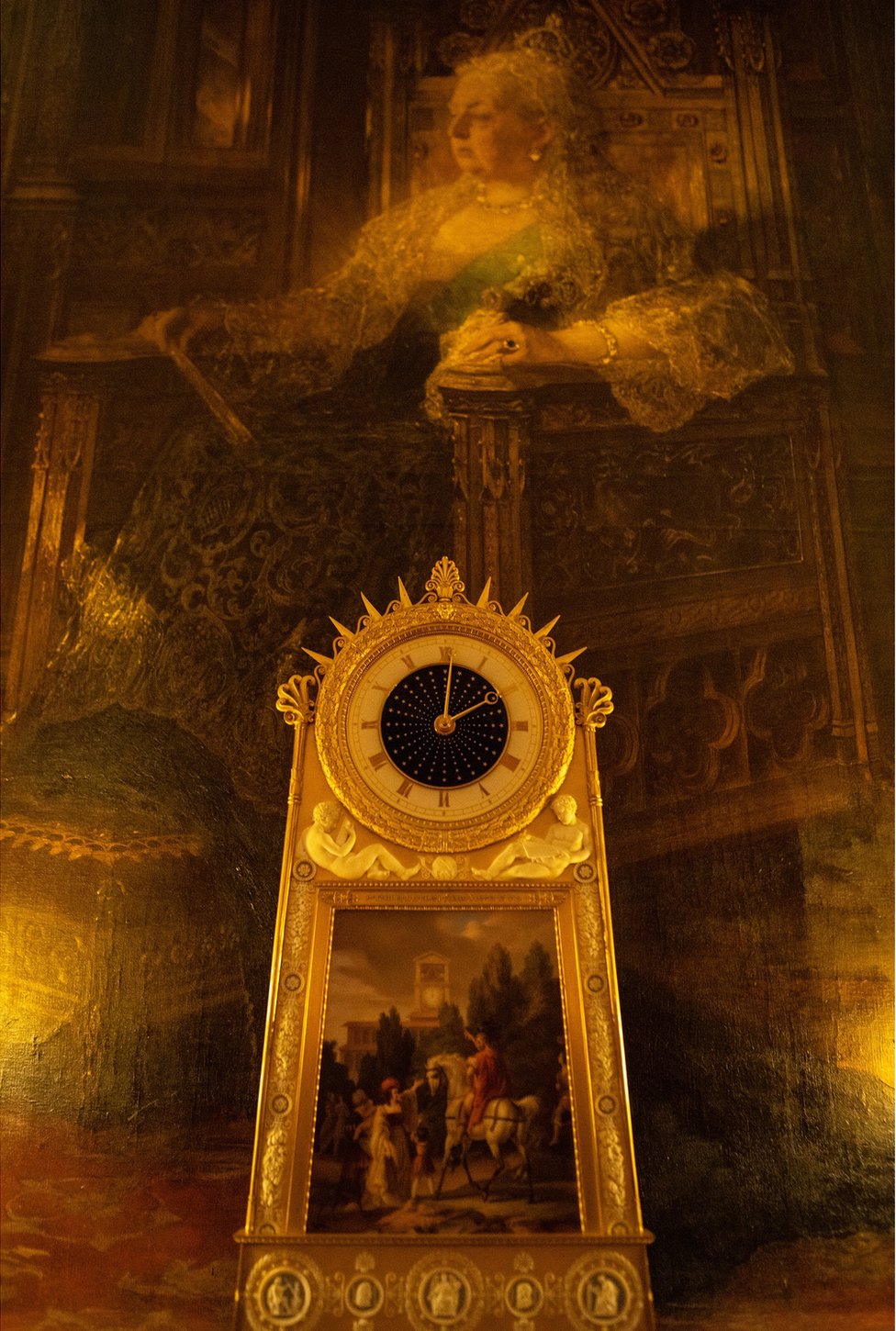 A beautiful clock with a large portrait of Queen Victoria behind it